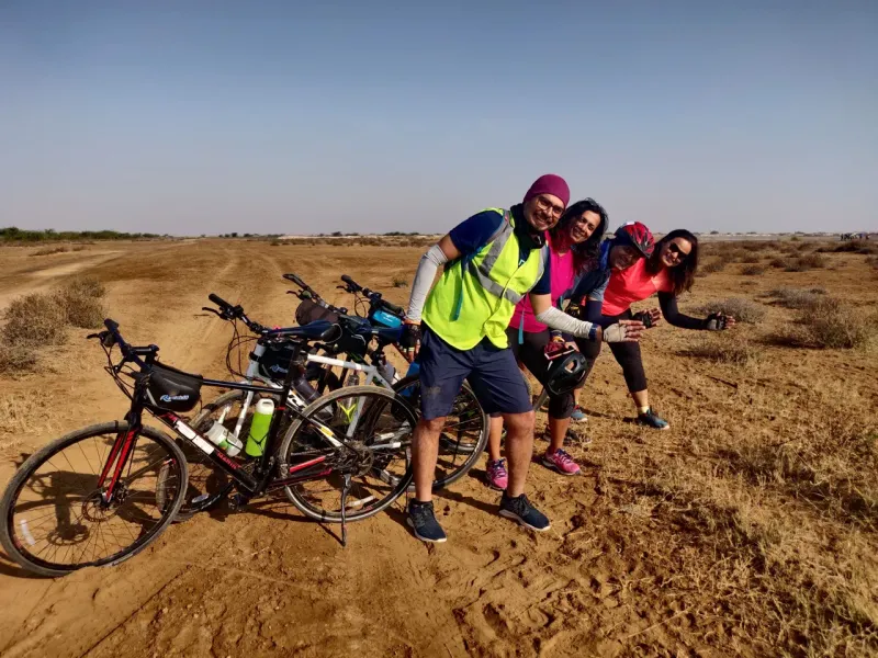 Riders posing with their bikes on a sandy track